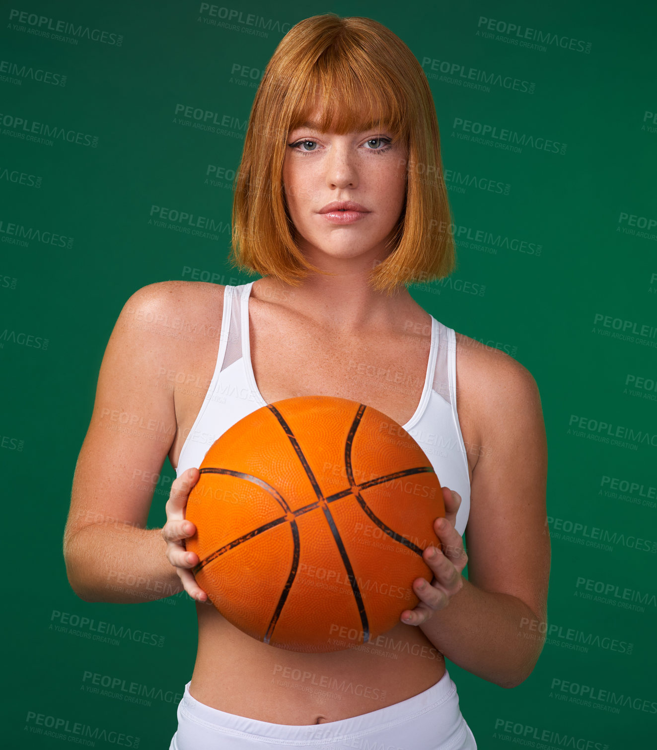 Buy stock photo Cropped shot of an attractive young sportswoman standing alone and holding a basketball against a green background in the studio