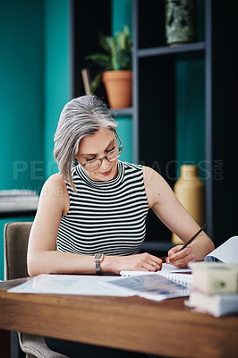 Buy stock photo Shot of of a mature businesswoman working on paperwork in her office
