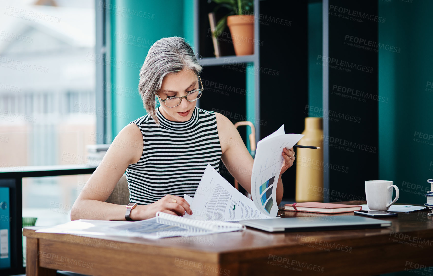 Buy stock photo Shot of of a mature businesswoman working on paperwork in her office