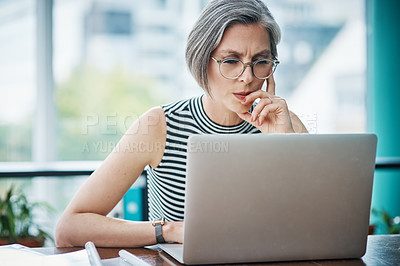 Buy stock photo Shot of a mature businesswoman using her laptop while sitting at her desk