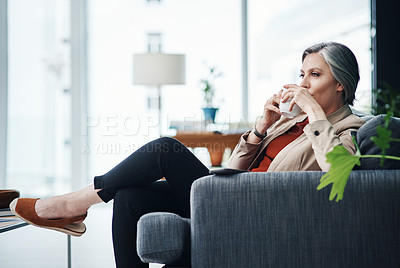 Buy stock photo Cropped shot of an attractive mature businesswoman sitting alone and enjoying a cup of coffee in her home office