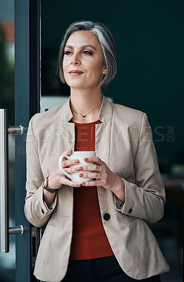 Buy stock photo Cropped shot of an attractive mature businesswoman standing alone and enjoying a cup of coffee in her home office