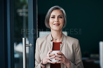 Buy stock photo Cropped portrait of an attractive mature businesswoman standing alone and enjoying a cup of coffee in her home office