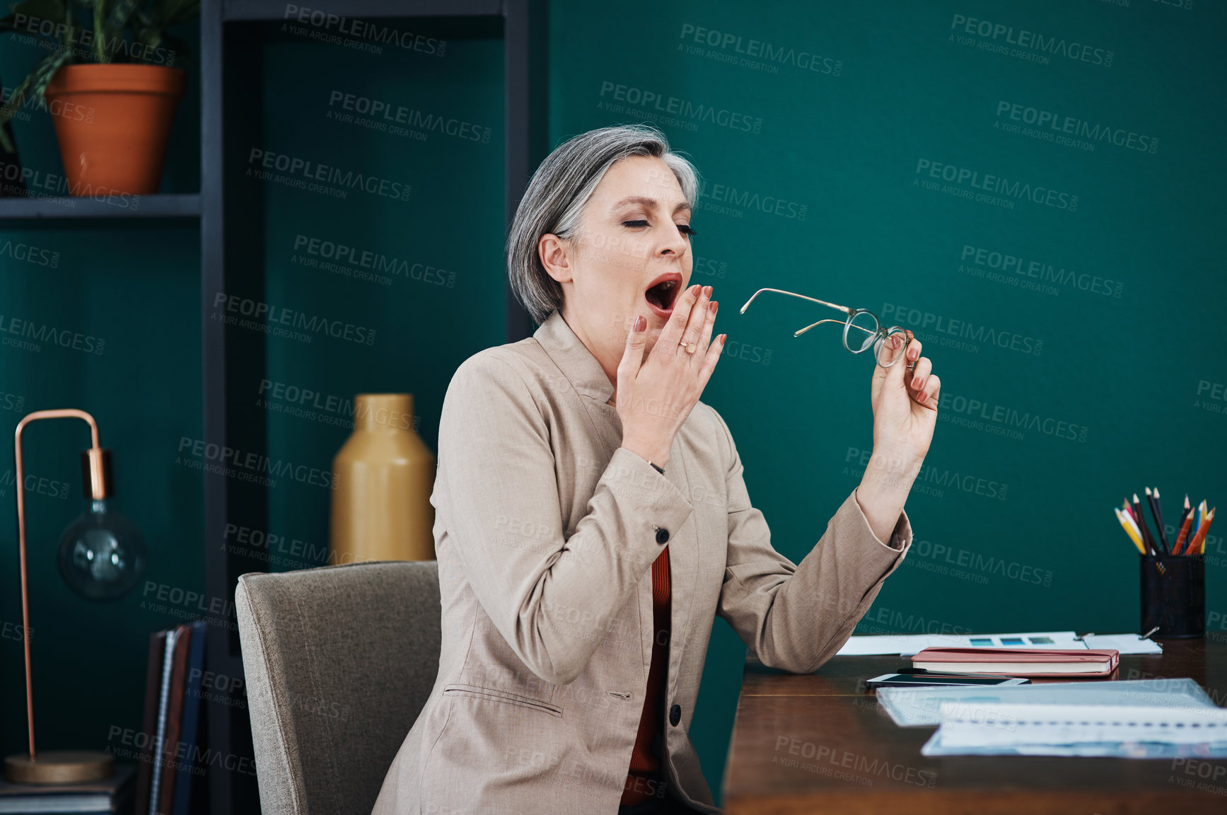 Buy stock photo Cropped shot of an attractive mature businesswoman sitting alone and yawning in her home office