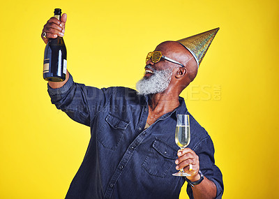 Buy stock photo Cropped shot of a cheerful senior man celebrating and drinking champagne in studio against a yellow background