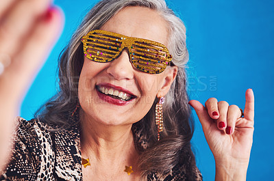 Buy stock photo Senior woman, selfie and sunglasses for fun, fashion and funky weekend party with pov in studio. Elderly person, shaka and memory on blue background for celebration, social media and profile picture 