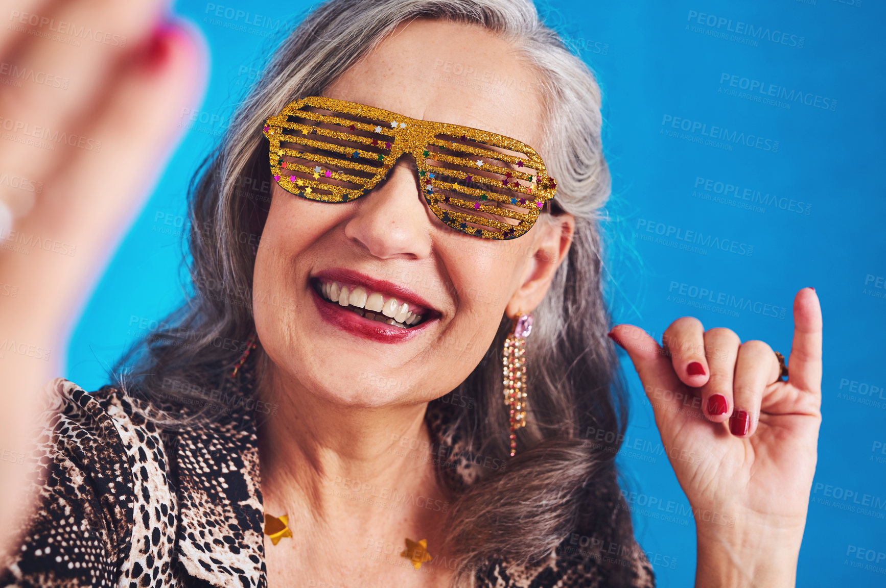 Buy stock photo Portrait of a funky and cheerful senior woman taking selfies against a blue background