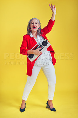 Buy stock photo Full length shot of a funky and stylish senior woman dancing while holding a boombox against a yellow background