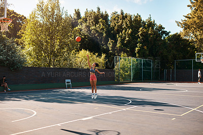 Buy stock photo Shot of a sporty young woman throwing a basketball into a net on a sports court