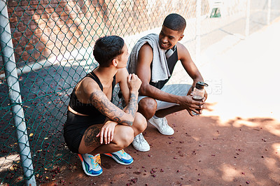 Buy stock photo Shot of two sporty young people chatting to each other against a fence outdoors