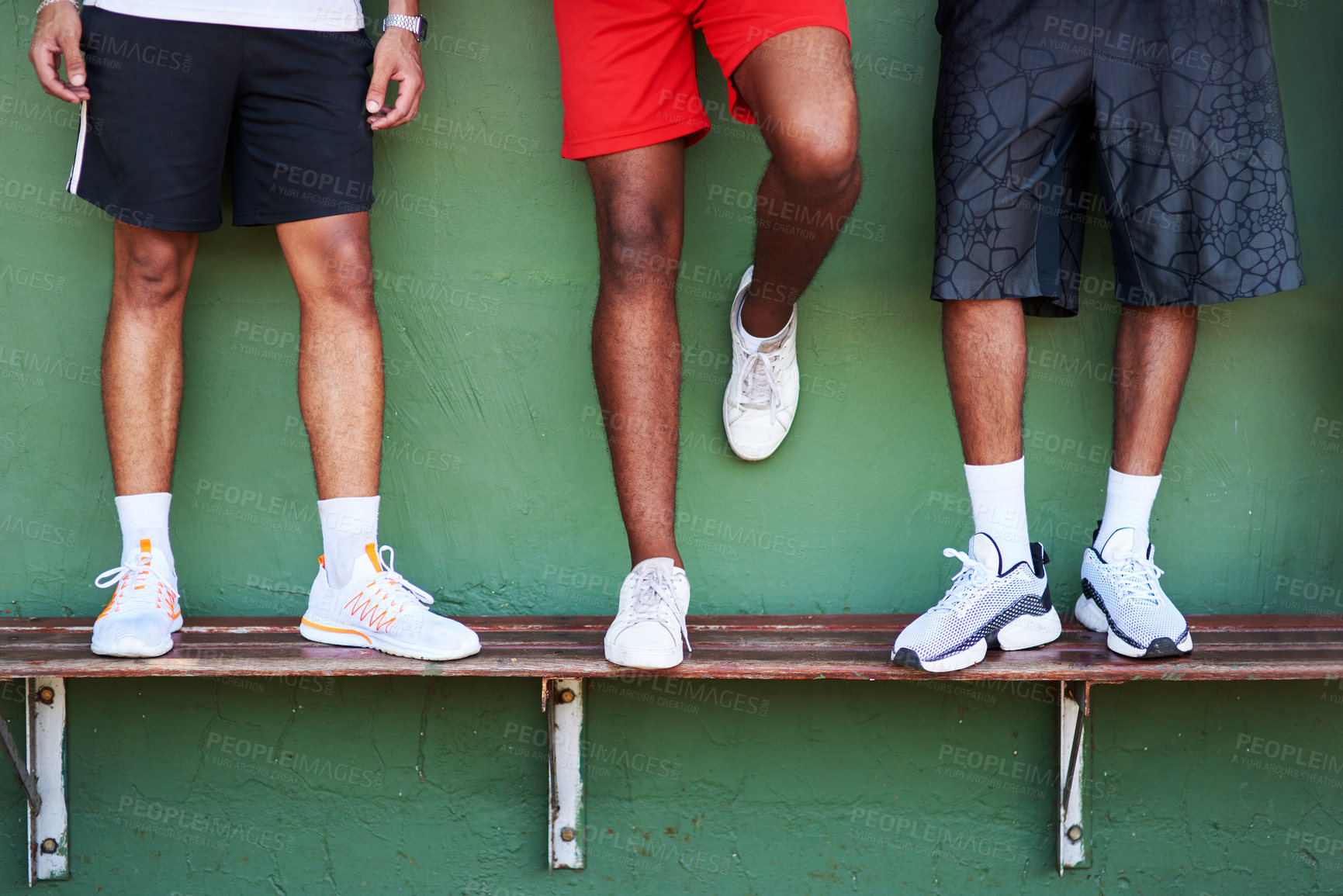 Buy stock photo Closeup shot of a group of sporty men standing on a bench against a wall