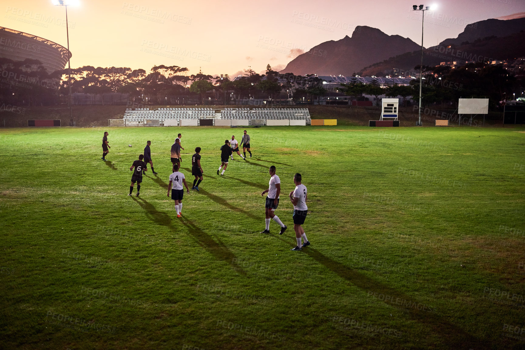 Buy stock photo Full length shot of a diverse group of sportsmen playing rugby at dusk in a sports club