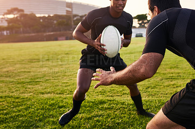 Buy stock photo Cropped shot of two handsome sportsmen playing rugby during a training session during the day