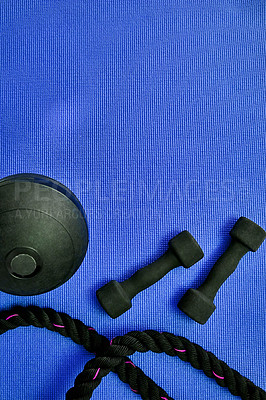 Buy stock photo High angle shot of two lightweight dumbbells and piece of rope placed on a blue background inside of a studio
