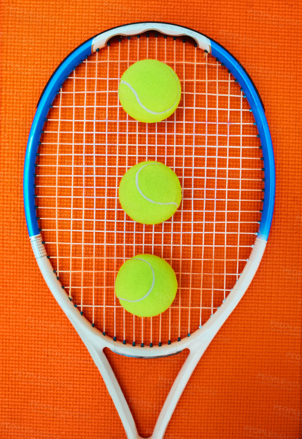 Buy stock photo High angle shot of a single tennis racket and a few tennis balls placed on an orange background inside of a studio