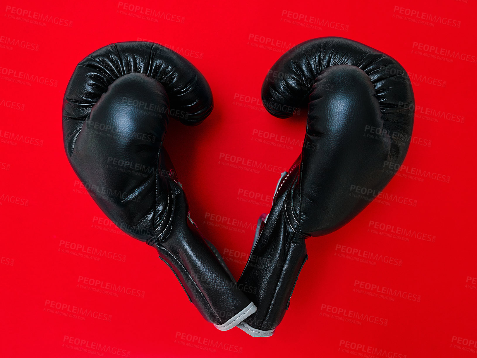 Buy stock photo High angle shot of a pair of boxing gloves placed together on top of a red background inside of a studio