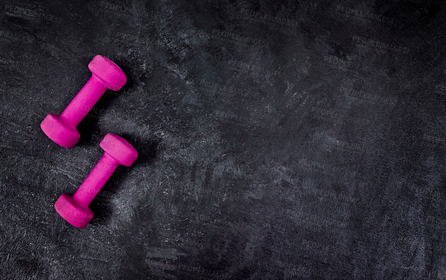 Buy stock photo High angle shot of two lightweight dumbbells placed on a dark background inside of a studio