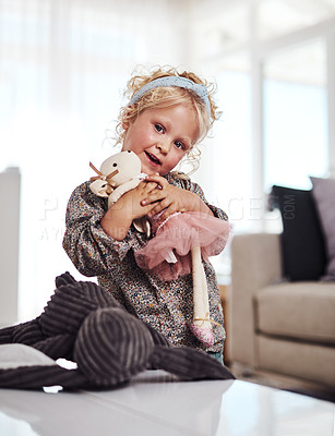 Buy stock photo Cropped portrait of an adorable little girl standing alone in the living room and playing with her toys at home
