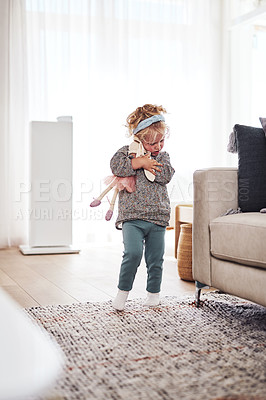 Buy stock photo Full length shot of an adorable little girl standing in the living room and playing with her toys at home