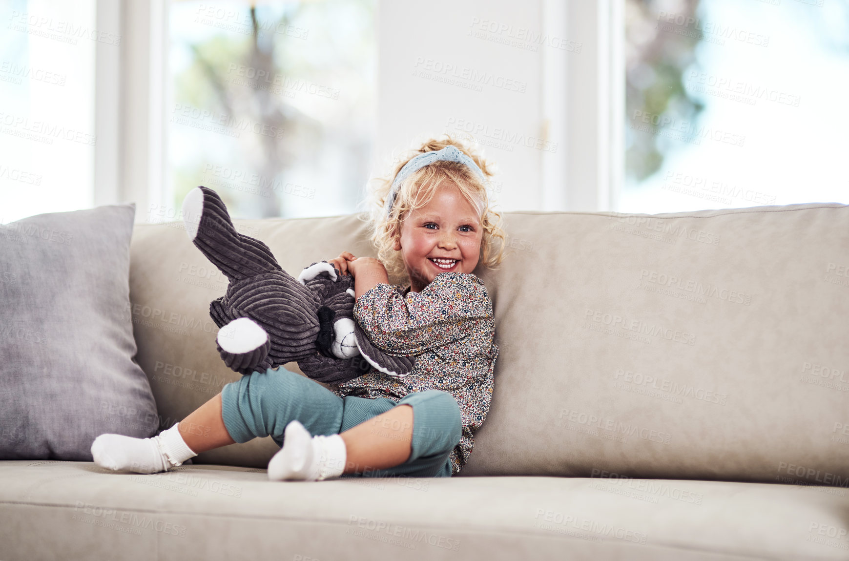 Buy stock photo Full length shot of an adorable little girl sitting alone on the sofa and playing with her toys at home