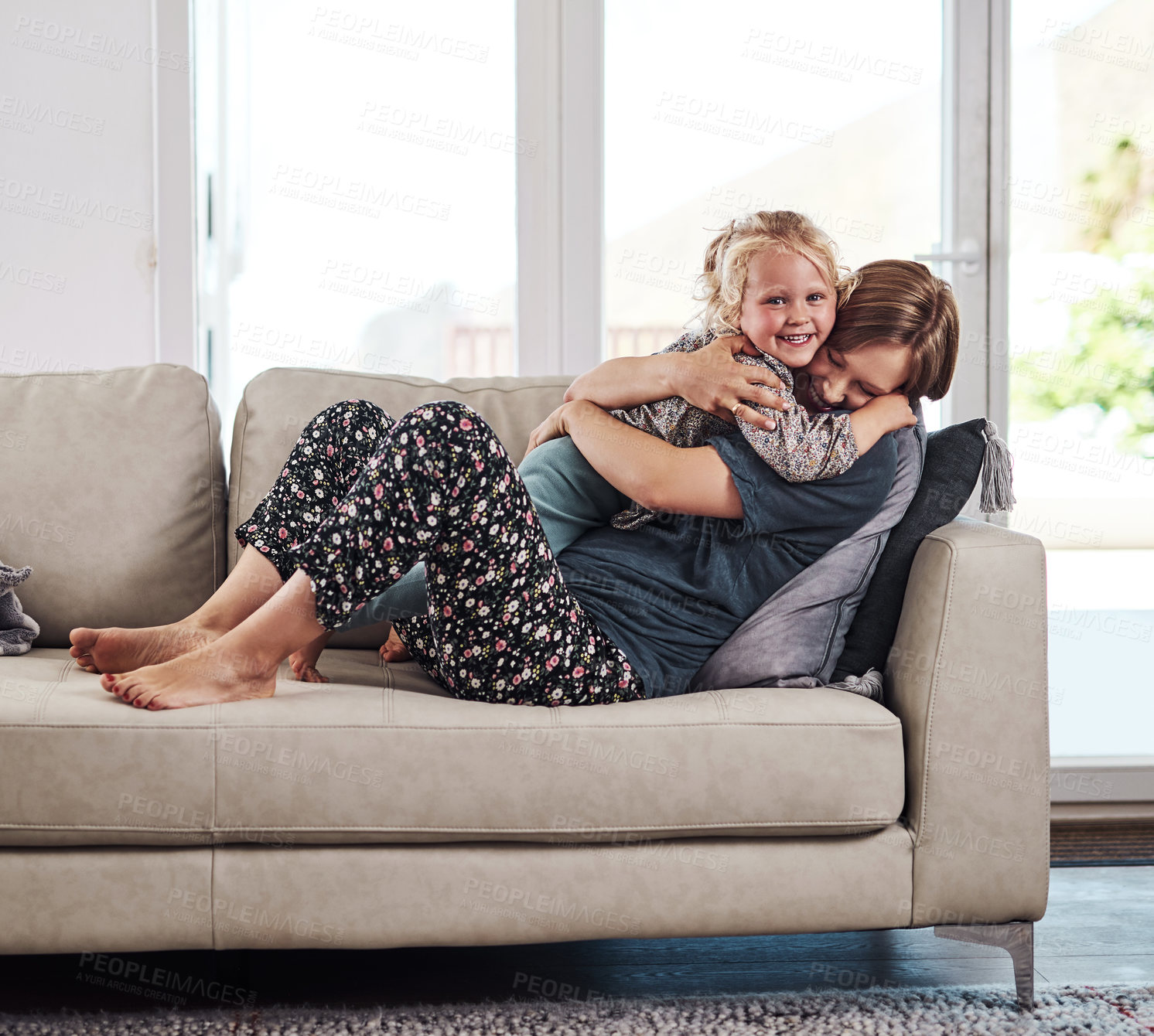 Buy stock photo Full length portrait of an attractive young mother sitting on the sofa and hugging her daughter at home