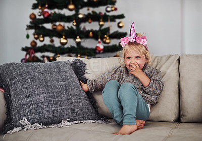 Buy stock photo Full length shot of an adorable little girl sitting alone on the sofa during a day at home