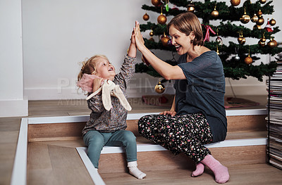 Buy stock photo Full length shot of an attractive young mother sitting and giving her daughter a high five at home