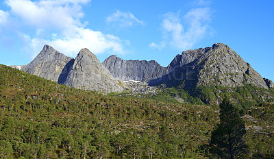 Buy stock photo Landscape view of mountains in Bodo. Majestic rocky peak surrounded by trees and cloudy blue sky during the day in Europe. Travel to Norway and take a trip in nature for an adventure