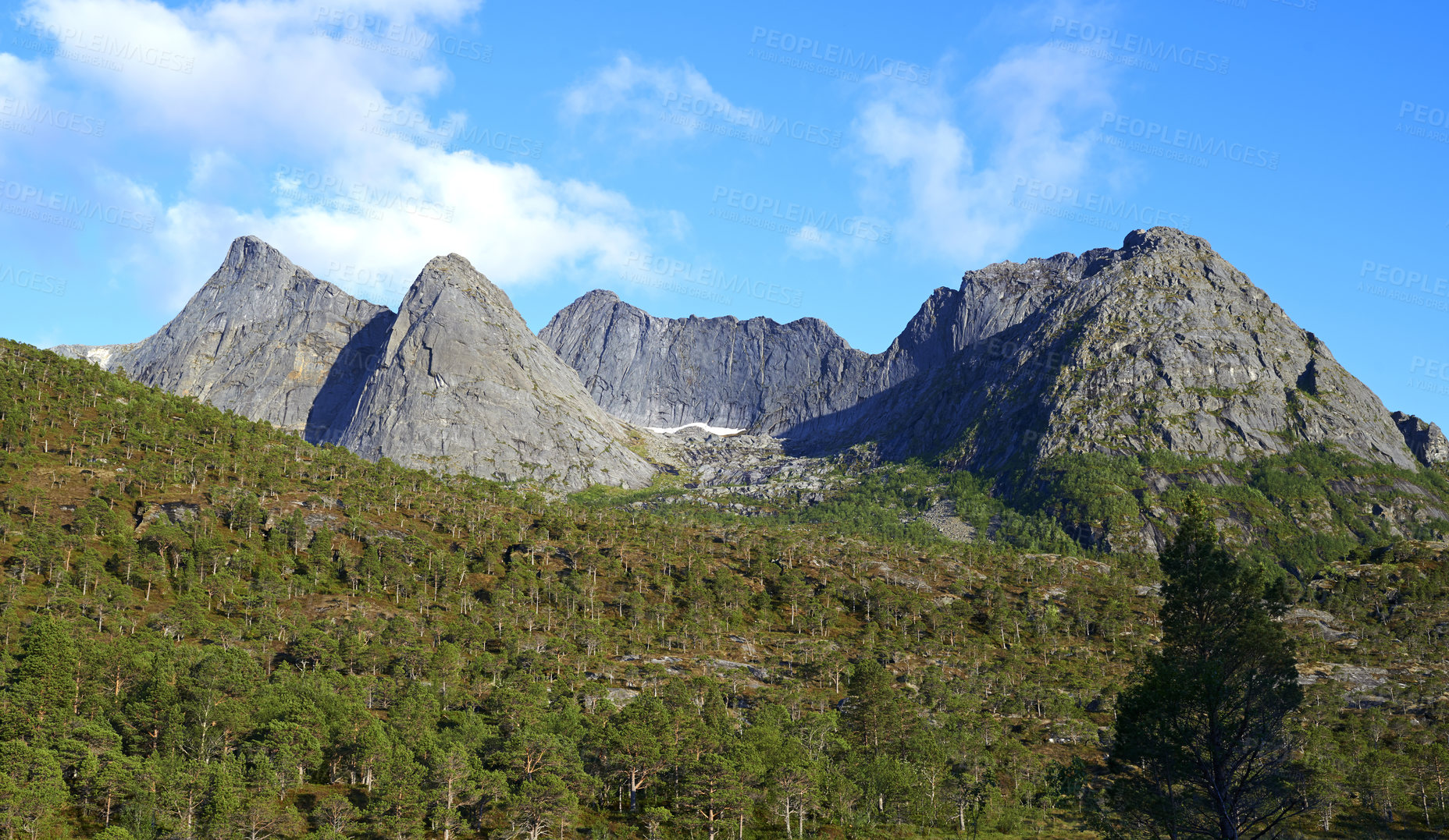 Buy stock photo Landscape view of mountains in Bodo. Majestic rocky peak surrounded by trees and cloudy blue sky during the day in Europe. Travel to Norway and take a trip in nature for an adventure