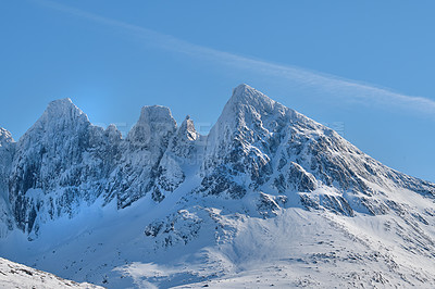 Buy stock photo A cold mountain peak covered in snow during winter with a blue sky background. Beautiful landscape of a snowy summit with freezing weather conditions in the morning outdoors in nature 