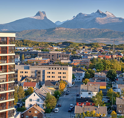 Buy stock photo A small city surrounded by nature with a mountain in the background. A landscape of buildings in a scenic vacation location. Cityscape of an urban town as a holiday destination