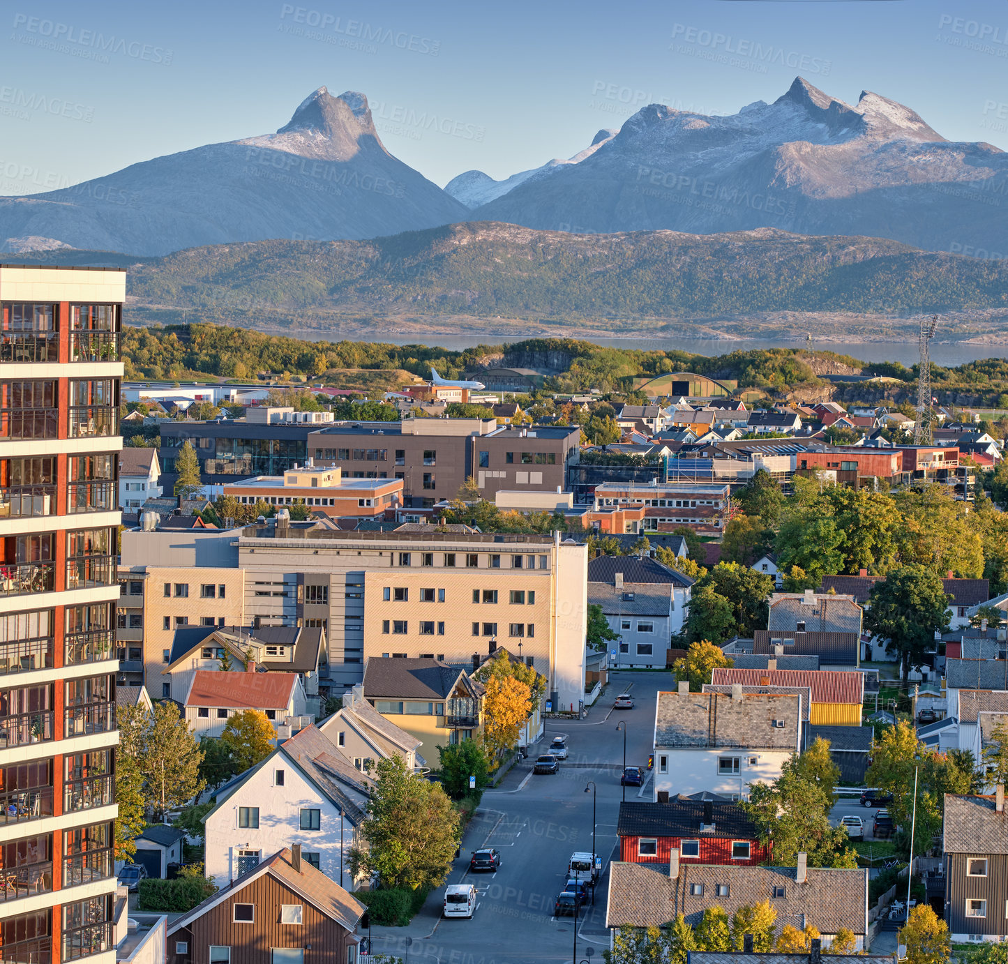 Buy stock photo A small city surrounded by nature with a mountain in the background. A landscape of buildings in a scenic vacation location. Cityscape of an urban town as a holiday destination