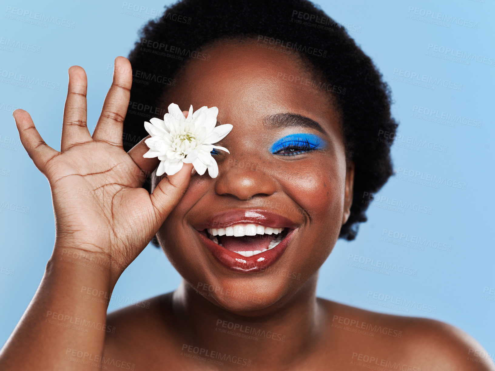 Buy stock photo Studio shot of a beautiful young woman covering her eye with a flower against a blue background