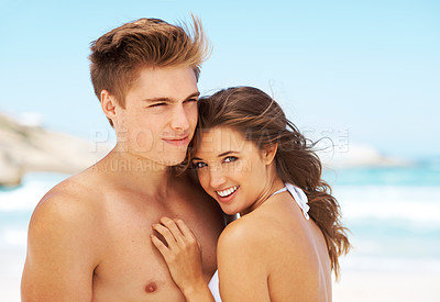 Buy stock photo Cropped shot of an affectionate young woman standing with her boyfriend at the beach during the day