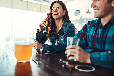 Buy stock photo Shot of a happy young man and woman having beers at a bar