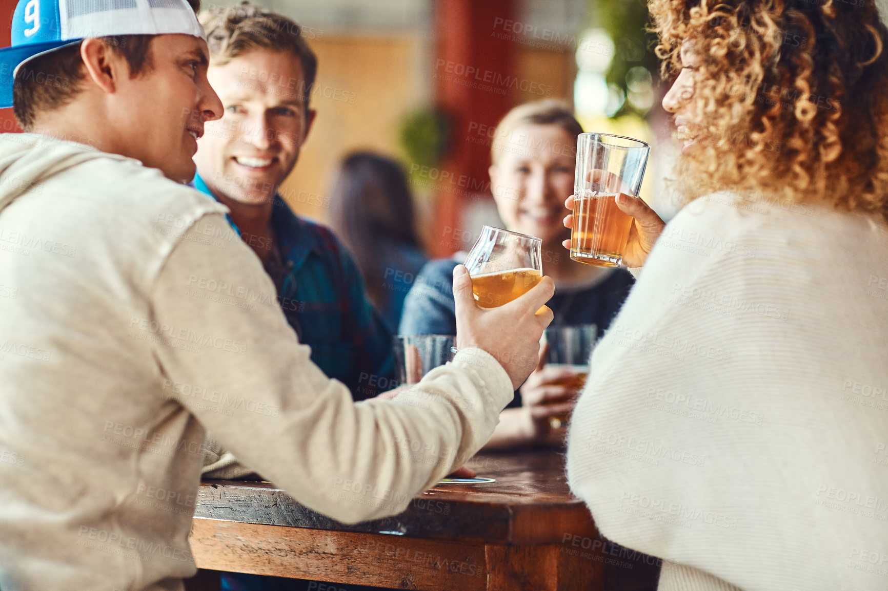 Buy stock photo Shot of a group of happy friends toasting with beers at a bar