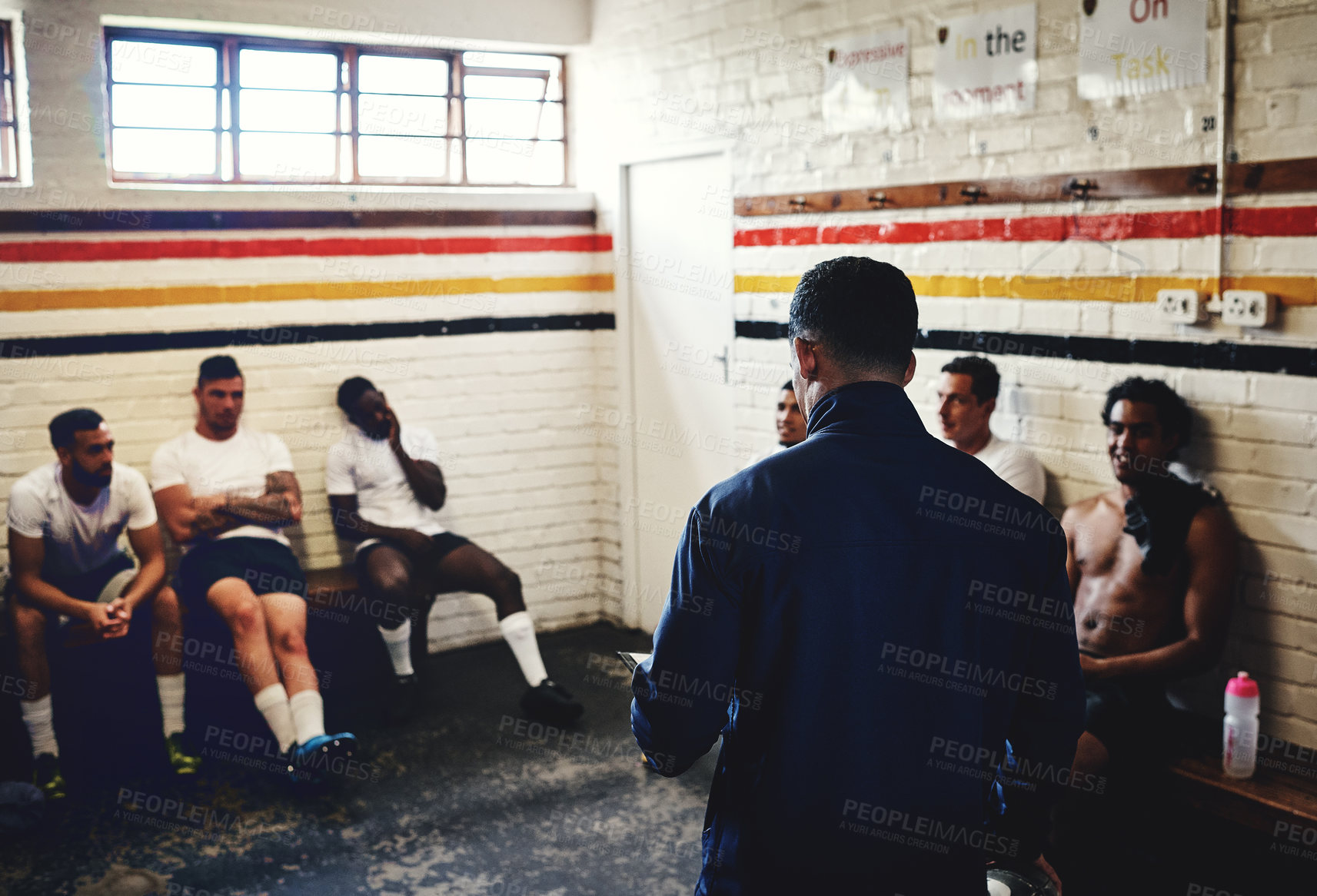 Buy stock photo Cropped shot of a rugby coach addressing his team players in a locker room during the day