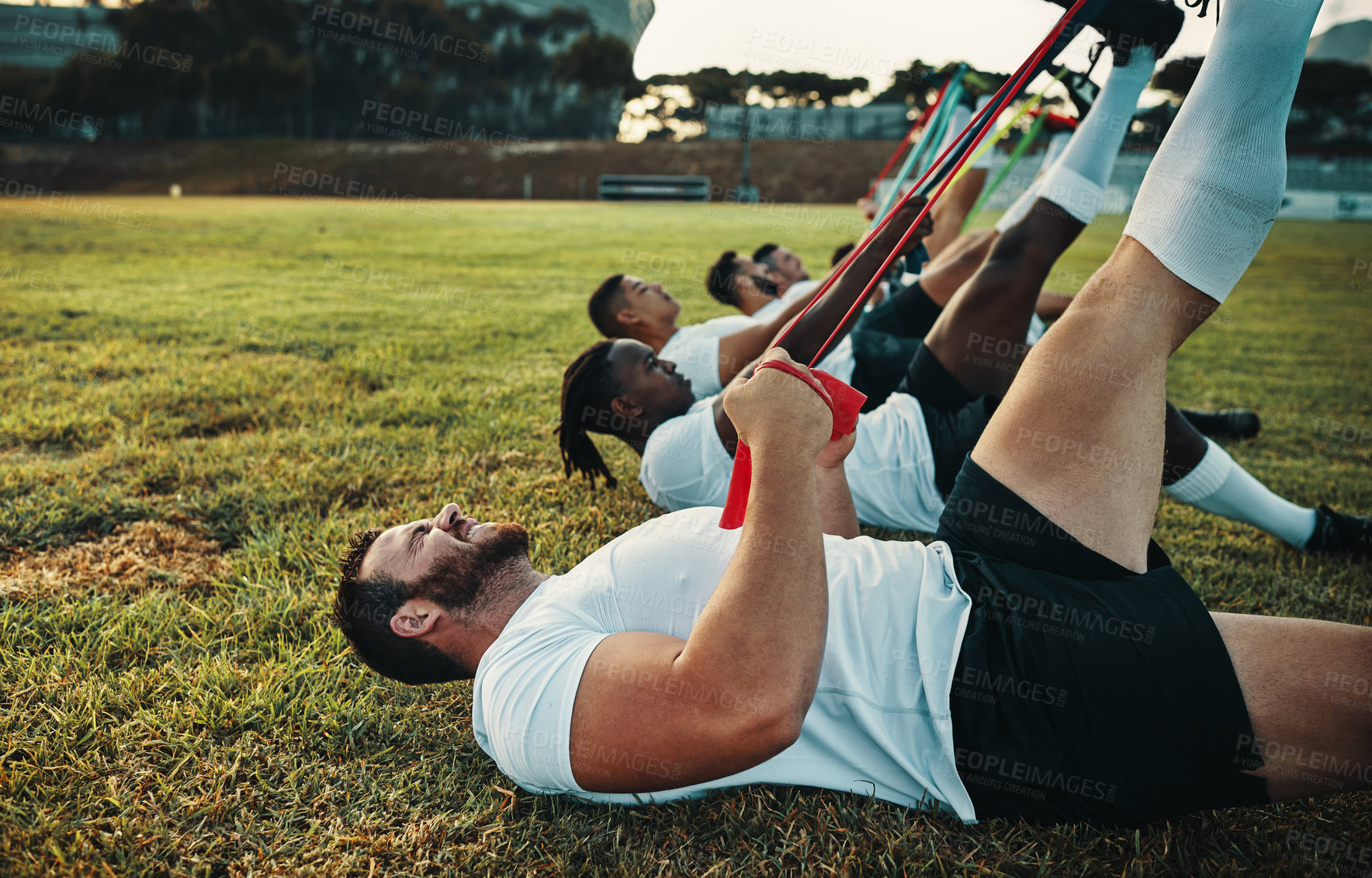 Buy stock photo Cropped shot of a group of young rugby players training with bands on the field during the day