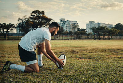 Buy stock photo Full length shot of a handsome young rugby player preparing for a kick while training on the field during the day