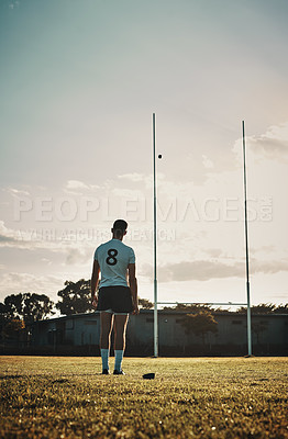 Buy stock photo Rearview shot of a handsome young rugby player kick  training on the field during the day