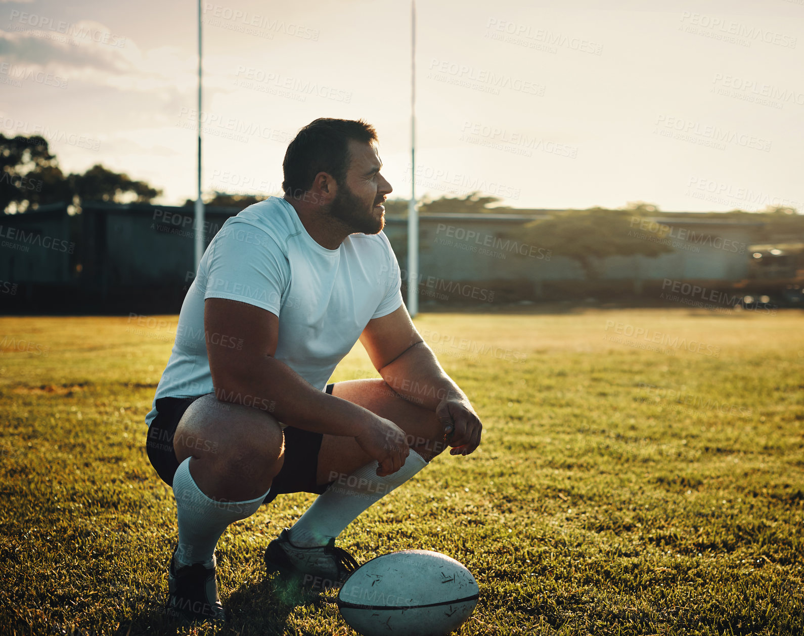 Buy stock photo Full length shot of a handsome young rugby player crouching on the field during the day