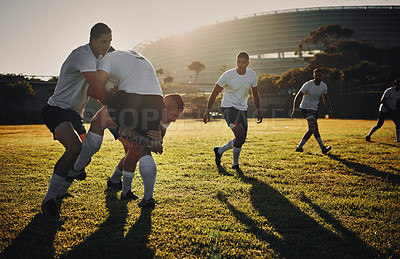 Buy stock photo Full length shot of a group of rugby players tackling during a training session on the field