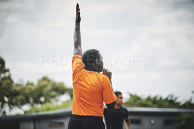 Buy stock photo Cropped shot of a referee blowing his whistle while lifting his hand up in the middle of a rugby match on a field during the day