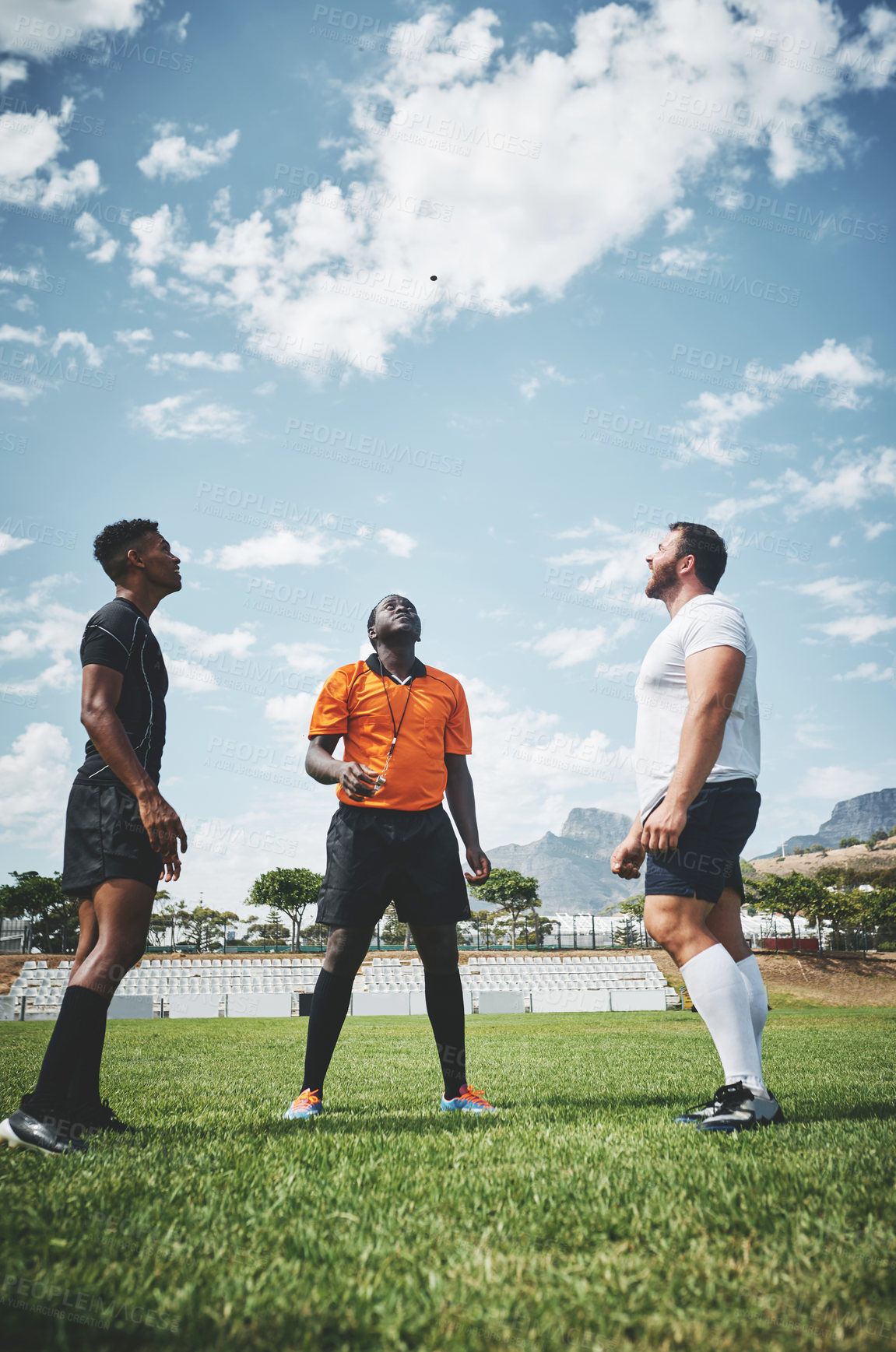 Buy stock photo Shot a referee flipping a coin among two rugby team captains to see who will start the kickoff of the match outside during the day
