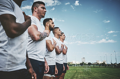 Buy stock photo Cropped shot of a team of confident young rugby players standing at attention singing their anthem outside on a field before a rugby match