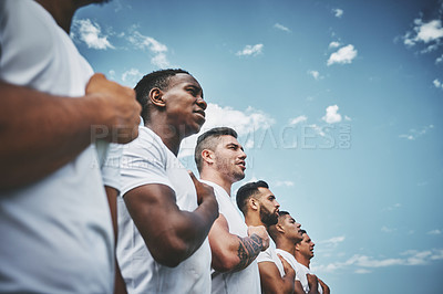 Buy stock photo Cropped shot of a team of confident young rugby players standing at attention singing their anthem outside on a field before a rugby match