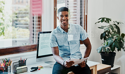 Buy stock photo Shot of a young businessman going over paperwork in a modern office