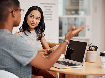 Buy stock photo Shot of a young businesswoman using a digital tablet while having a discussion with a colleague in an office