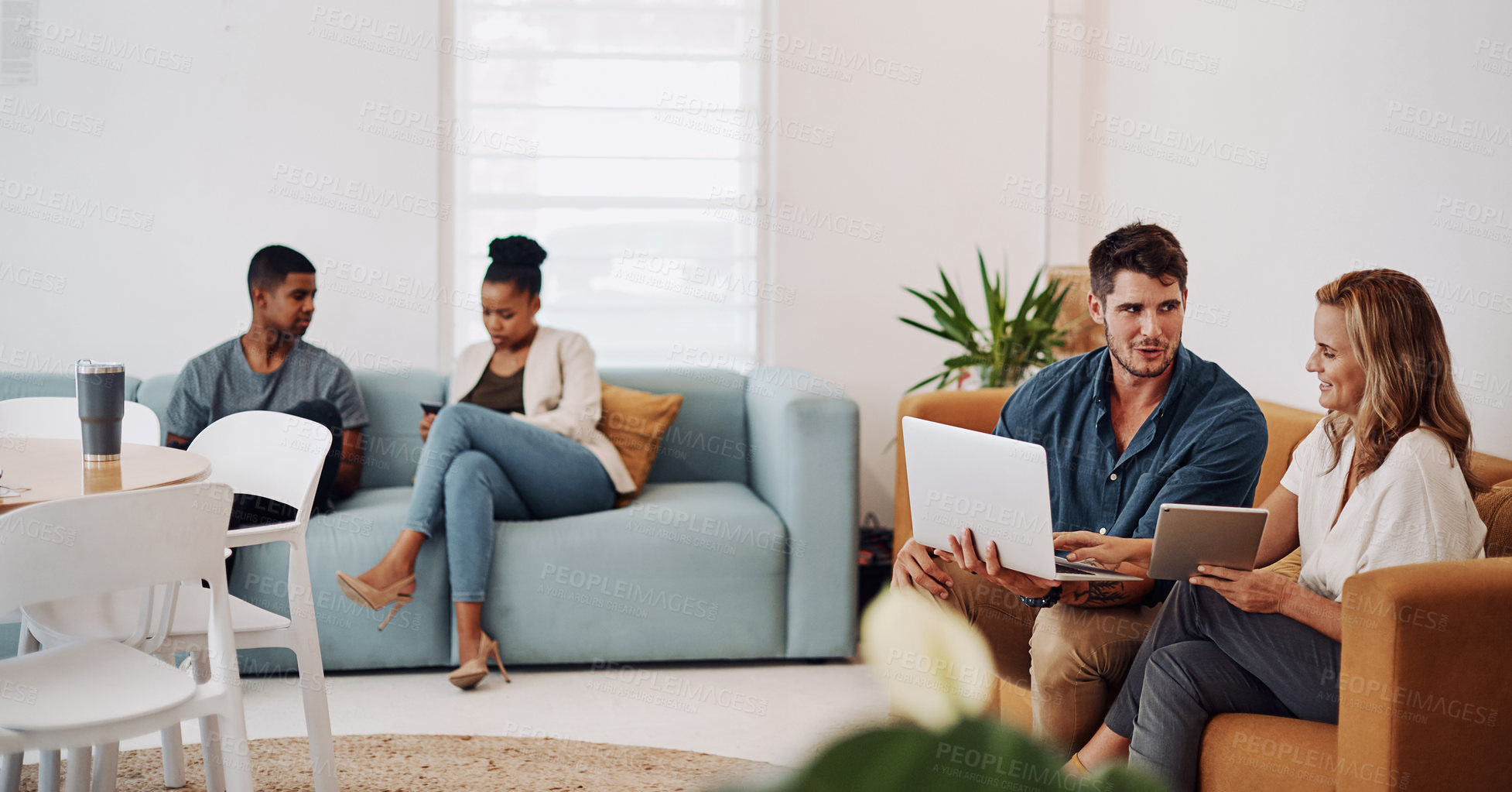 Buy stock photo Cropped shot of a young group of businesspeople sitting in the office together and working wth technology