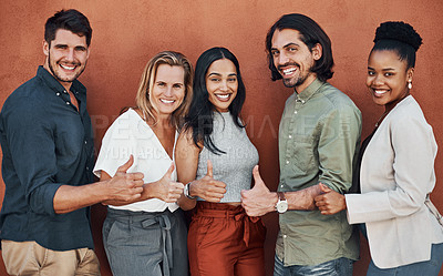 Buy stock photo Cropped portrait of a diverse group of businesspeople standing and making a thumbs up gesture against a wall outside